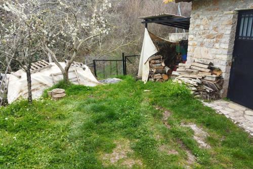 a yard with a house with a stack of logs at Stone Mountainhouse near Kalavryta, North Peloponnese, Greece in Dhoumená