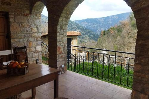 a room with a table and a balcony with a view at Stone Mountainhouse near Kalavryta, North Peloponnese, Greece in Dhoumená