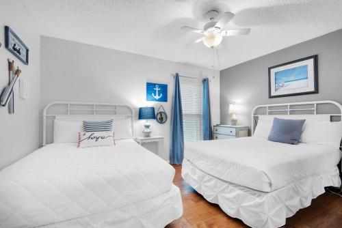 Un dormitorio con dos camas y un ventilador de techo. en Emerald Isle 208, en Fort Walton Beach
