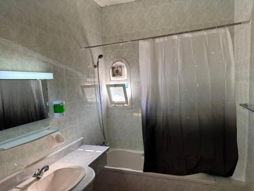a bathroom with a shower and a sink and a tub at Lunar Beach Hostel in Abu Dhabi