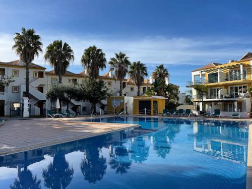 una piscina con palme e edifici di Grupo Morgado - Quinta do Morgado - Morgado Village a Tavira
