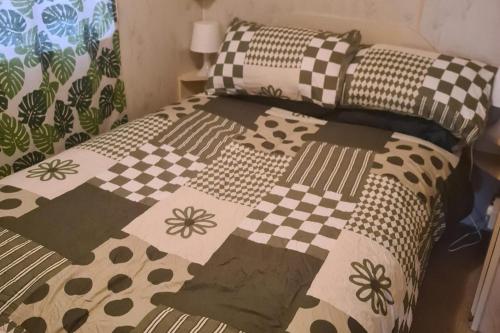 a bed with a checkered blanket and pillows at Cozy Cardiff Cabin Retreat sleeps 6 by Aimee in Cardiff