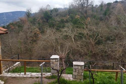 a view of a mountain with a fence and trees at Stone Mountainhouse near Kalavryta, North Peloponnese, Greece in Dhoumená