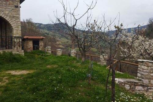 a stone building with a yard with a tree and a fence at Stone Mountainhouse near Kalavryta, North Peloponnese, Greece in Dhoumená