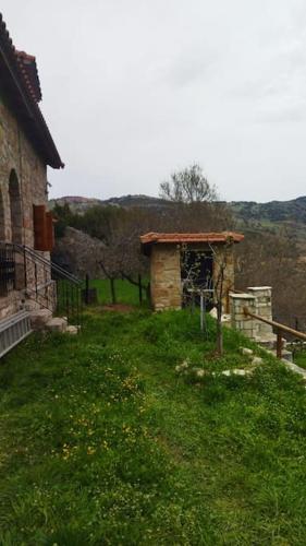 a small building in the grass next to a house at Stone Mountainhouse near Kalavryta, North Peloponnese, Greece in Dhoumená