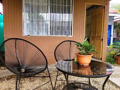two chairs and a table in front of a house at Tico Bed & Breakfast La Fortuna in Fortuna