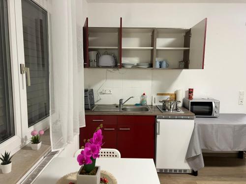 a kitchen with red cabinets and a table with purple flowers at Apartment Nr 7 am Stuttgarter Flughafen und Messe in Leinfelden-Echterdingen