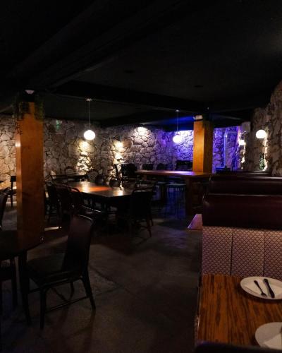 a restaurant with tables and chairs and a stone wall at Hotel Hacienda Santana in Tecate