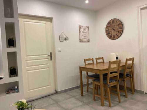 une salle à manger avec une table, des chaises et une horloge dans l'établissement Logement entier 3P proche centre ville, à Saint-Quentin