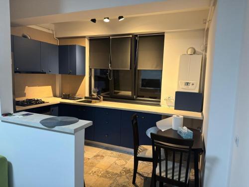 Una cocina con gabinetes azules y una mesa y sillas. en Apartament Central Craiova, en Craiova