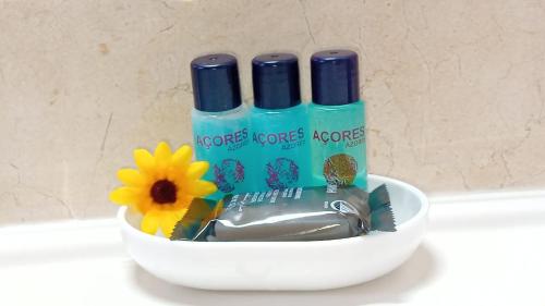 a bowl with two bottles of toothpaste and a flower at Sunflower Guest House - Madalena - Pico in São Caetano