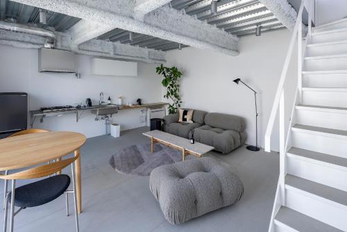 a living room with a staircase and a table at まえばしガレリアArt residence & Hotel in Maebashi