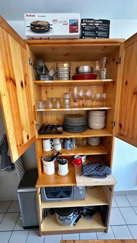 a kitchen cabinet with plates and dishes in it at Appartement Centre Ville pied de piste Briançon in Briançon