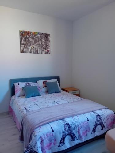 a bed in a bedroom with a picture on the wall at AlejaPark Inđija in Železnicka Stanica Inđija Selo