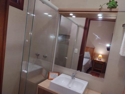 a bathroom with a sink and a shower with a mirror at Sobrado aconchegante em Nova Petrópolis-RS perto de Gramado in Nova Petrópolis