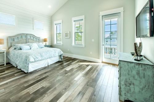 a bedroom with a bed and wooden floors and windows at Grayt Paradise in Grayton Beach