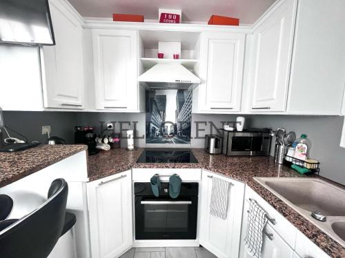 une cuisine blanche avec des armoires blanches et un micro-ondes dans l'établissement Deux pièces grand confort - A la frontière Monégasques, à Beausoleil