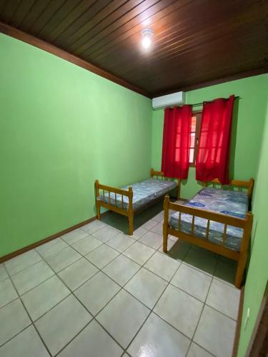 a room with two beds and red curtains at JOÃO CARLOS CASAS 3 Quartos Penha SC in Penha
