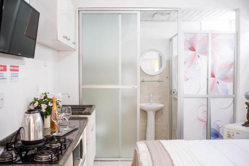 uma cozinha branca com um lavatório e um chuveiro em Pousada Cancun em Florianópolis