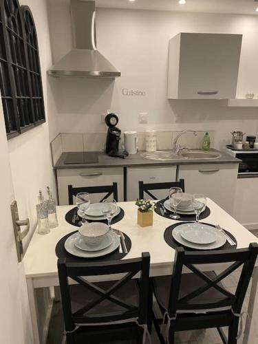 une cuisine avec une table, des chaises et des assiettes. dans l'établissement Superbe F2 - 1er étage proche centre ville 3P Wifi, à Saint-Quentin