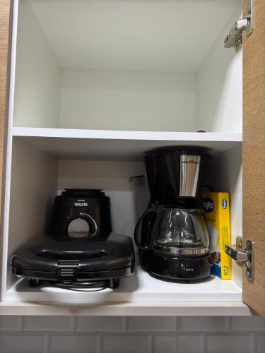 a coffeemaker and a coffee maker in a cabinet at Flat em Alter do Chão in Alter do Chao