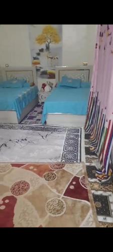 Un dormitorio con dos camas y una alfombra. en Nubian Village, West Aswan, en Fârouk