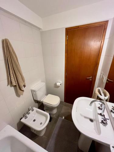 een witte badkamer met een toilet en een wastafel bij Departamento M&L in San Martín de los Andes