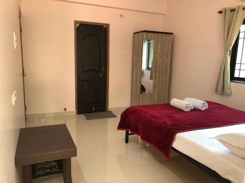 a bedroom with a bed with a red blanket and a mirror at Mahalaxmi Homestay II in Mapusa