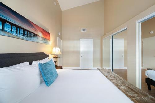 a bedroom with a large white bed with a blue pillow at Charming Beach Duplex Home in Corona del Mar in Newport Beach