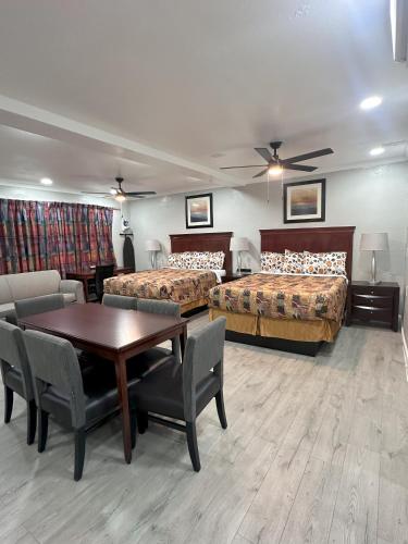 a hotel room with two beds and a table and chairs at Sunshine Inn & Suites Venice, Florida in Venice