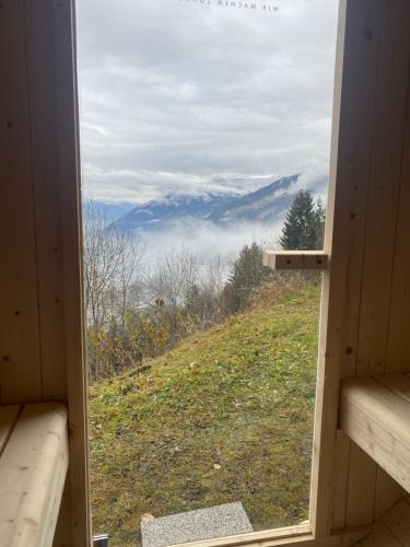 a window in a cabin with a view of a mountain at Sonnalm Panoramablick Garten Sauna in Rohrberg