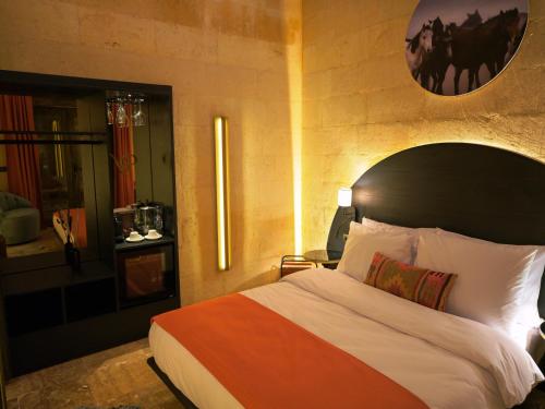 a bedroom with a bed with an orange and white comforter at Very Peri Cappadocia - The Lifestyle Luxury Design Hotel in Uchisar