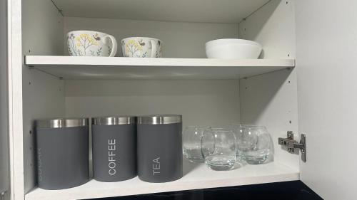 a shelf with cups and glasses on it at Guest Suite in Waterlooville in Waterlooville