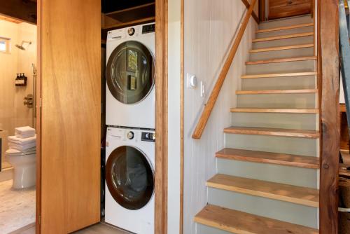 a laundry room with a washer and dryer next to a staircase at Treehouse - Close to Slopes, Hot Tub, Gourmet Kitchen, Deck in Big Bear Lake