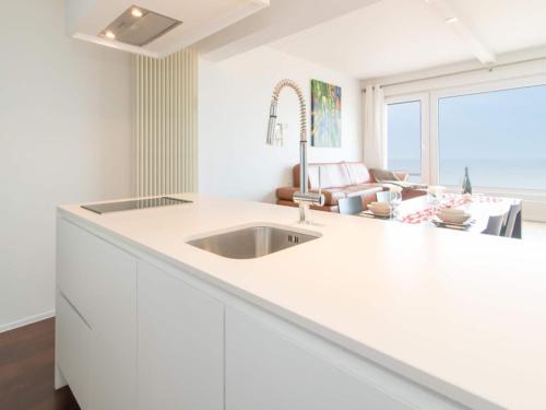 a white kitchen with a sink and a living room at Studio in Ostend near Beach and Promenade in Ostend