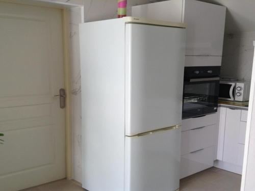 - un réfrigérateur blanc dans une cuisine avec des placards blancs dans l'établissement Charming town centre house with garden, à Dax