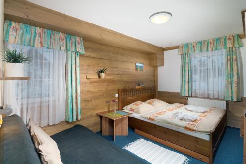 1 dormitorio con cama y sofá en Pension and Apartments MONIKA, en Špindlerův Mlýn