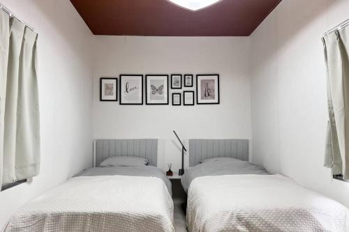 two beds in a room with white walls at 岡山駅から徒歩7分の一軒家 in Okayama