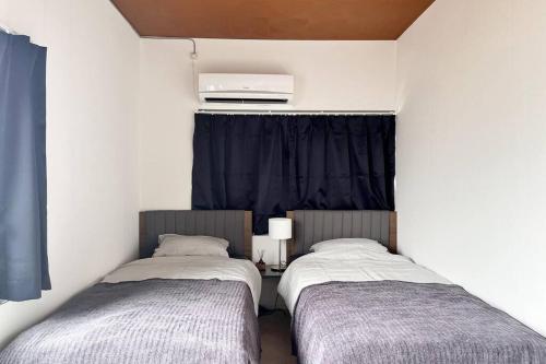 two twin beds in a room with a window at 岡山駅から徒歩7分の一軒家 in Okayama