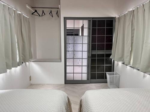a white room with two beds and a window at 岡山駅から徒歩7分の一軒家 in Okayama