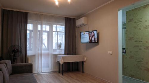a living room with a table and a tv on the wall at Apartment near city center on Peremohy Avenue 46 in Chernihiv