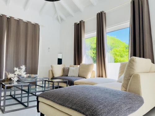 a living room with white furniture and a large window at Atypik Villa in Cul de Sac