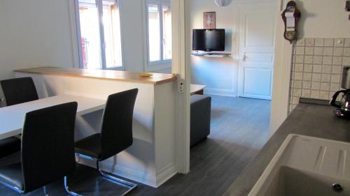 a room with a table and chairs and a tv at Gîte du Vignoble in Beblenheim