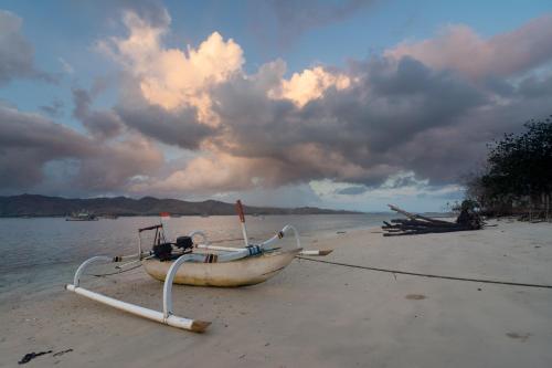 a boat on the shore of a beach at Camp Gili X - Gili Tangkong Island in Pulau Gilinanggu