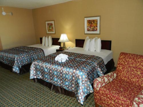 a hotel room with two beds and a chair at California Inn Barstow in Barstow