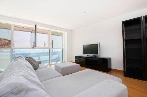 a living room with a white couch and a television at River View Luxury Apartment in Cruz Quebrada