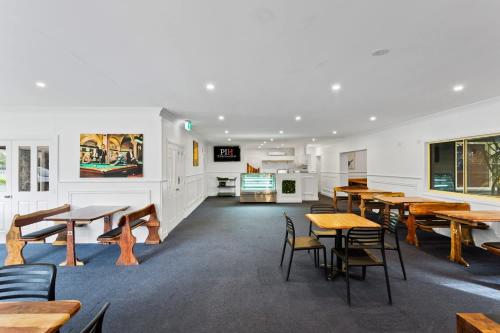 a cafeteria with wooden tables and chairs in a building at Phillip Island Family Resort 2Bdr in Cowes
