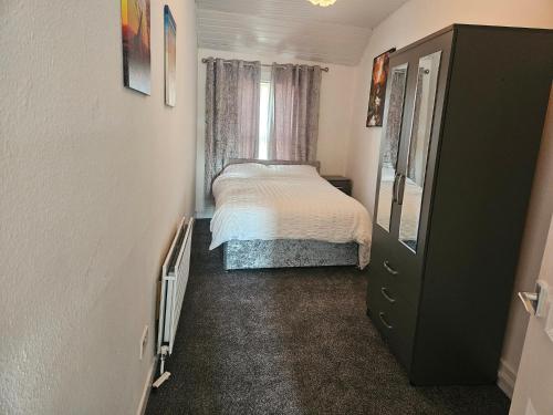 a small bedroom with a bed and a dresser at Liverpool Haven, Stylish and Spacious 3-Bedroom Apartment with City Access in Liverpool