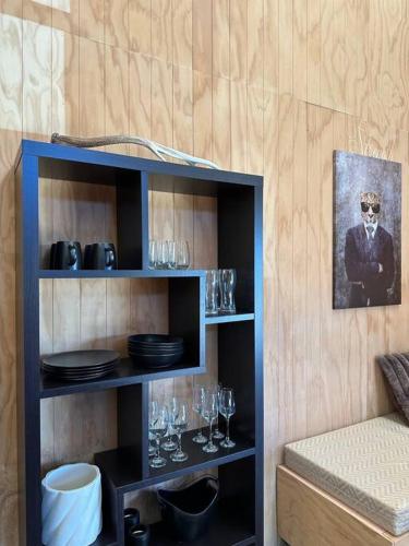 a shelf with glasses and plates and a picture of a man at Mount Jowett Retreat in Whanganui