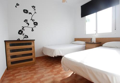 a bedroom with two beds and a dresser in it at BBQ Evita Beach Club in Benalmádena